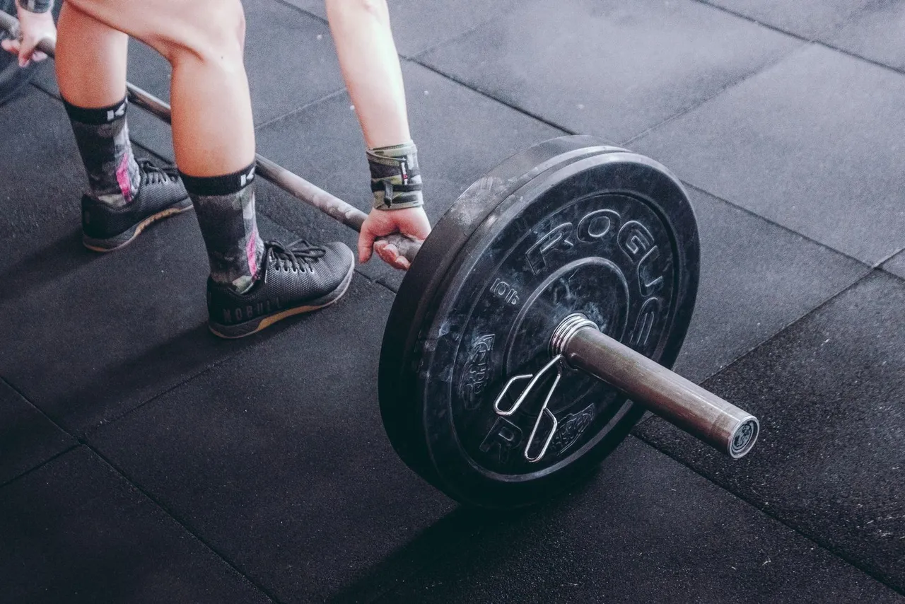 Hands on a black and grey loaded barbell